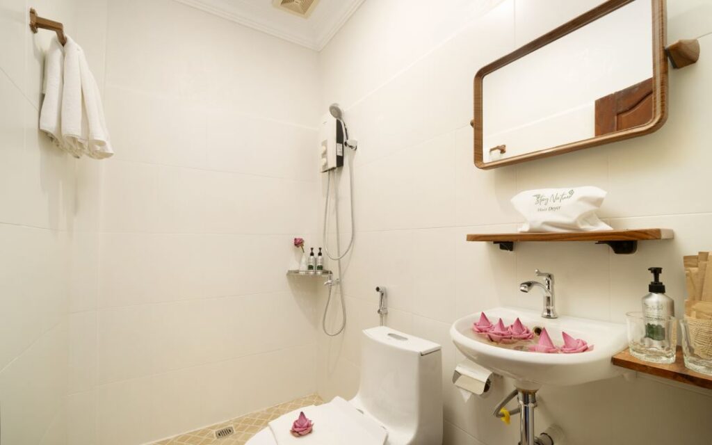 Bathroom at the Tree Hotel with shower, toilet, sink, mirror, and flower decorations.